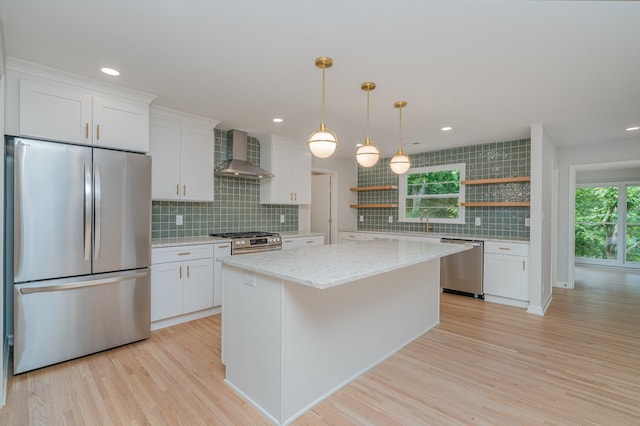 kitchen with stainless steel appliances, light hardwood / wood-style floors, white cabinets, a kitchen island, and wall chimney exhaust hood