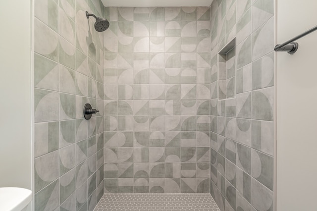 bathroom featuring toilet and a tile shower