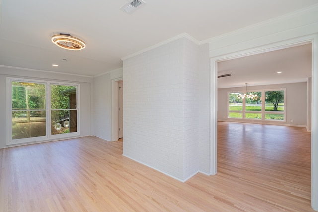 empty room with crown molding, light hardwood / wood-style floors, and brick wall