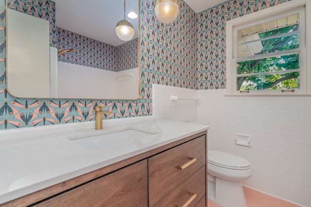 bathroom with vanity, toilet, and tile walls