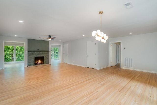 unfurnished living room featuring ceiling fan with notable chandelier and light wood-type flooring