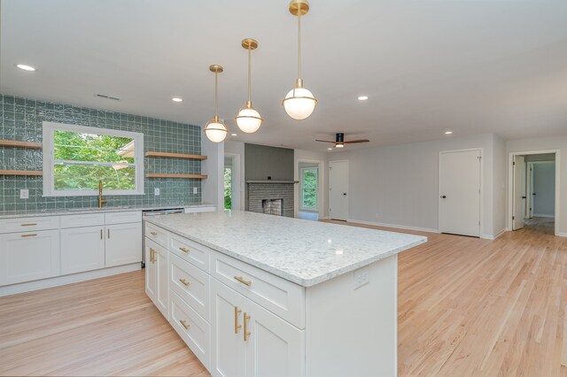 kitchen featuring decorative backsplash, decorative light fixtures, a center island, and white cabinets