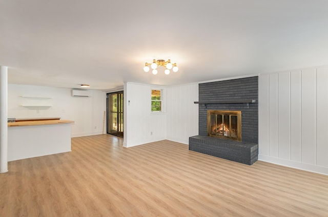 unfurnished living room with a fireplace, light hardwood / wood-style floors, and an AC wall unit