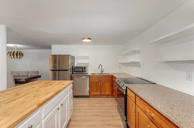 kitchen with wood counters, sink, white cabinetry, appliances with stainless steel finishes, and light hardwood / wood-style floors