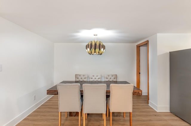 dining space with an inviting chandelier and light hardwood / wood-style flooring