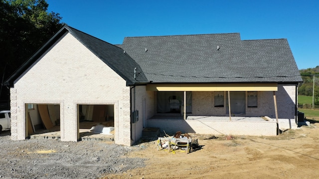 rear view of property featuring a garage and a patio area