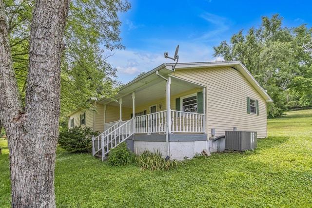 exterior space featuring covered porch, cooling unit, and a front yard