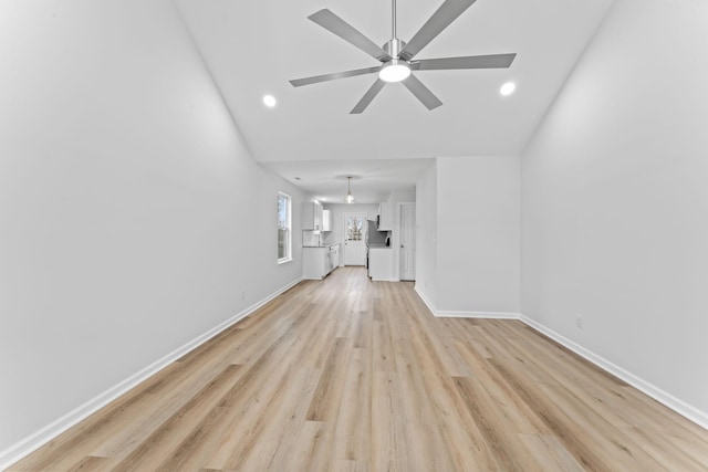 unfurnished living room with lofted ceiling, light wood-style floors, ceiling fan, and baseboards