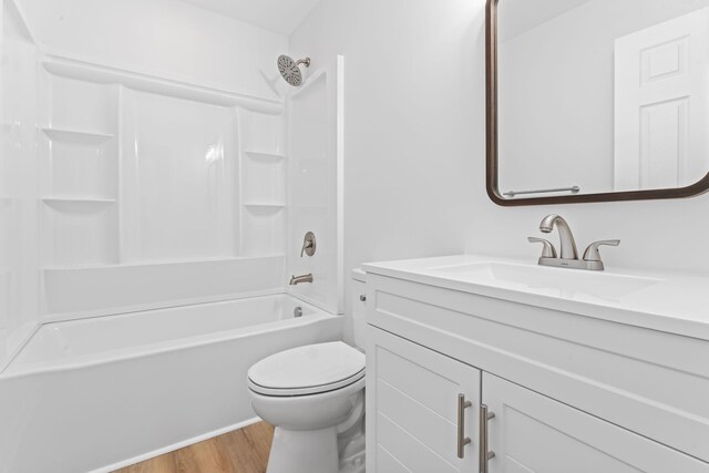 bathroom featuring toilet,  shower combination, wood finished floors, and vanity