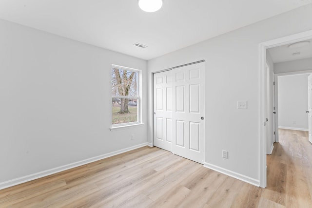 unfurnished bedroom with light wood-style flooring, a closet, visible vents, and baseboards