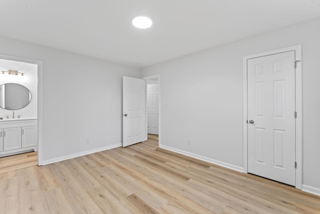 unfurnished bedroom with a sink, light wood-style floors, connected bathroom, and baseboards