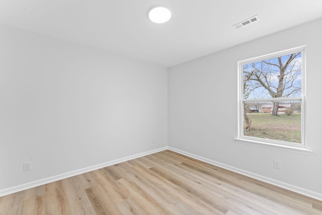 empty room featuring light wood-type flooring, visible vents, baseboards, and a wealth of natural light