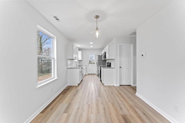 kitchen featuring visible vents, backsplash, appliances with stainless steel finishes, white cabinetry, and baseboards