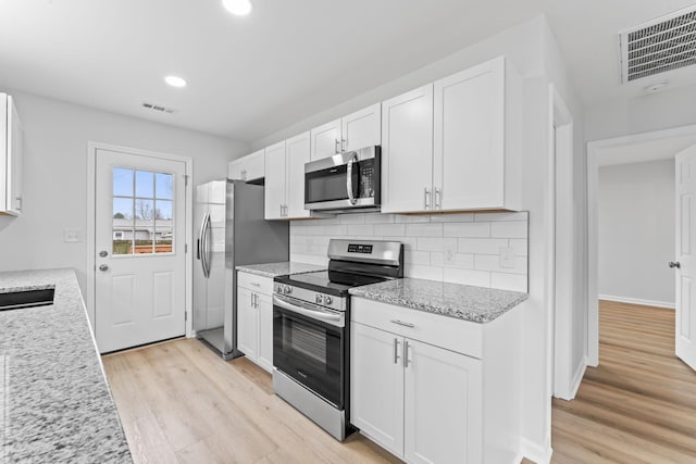 kitchen with appliances with stainless steel finishes, visible vents, and white cabinets