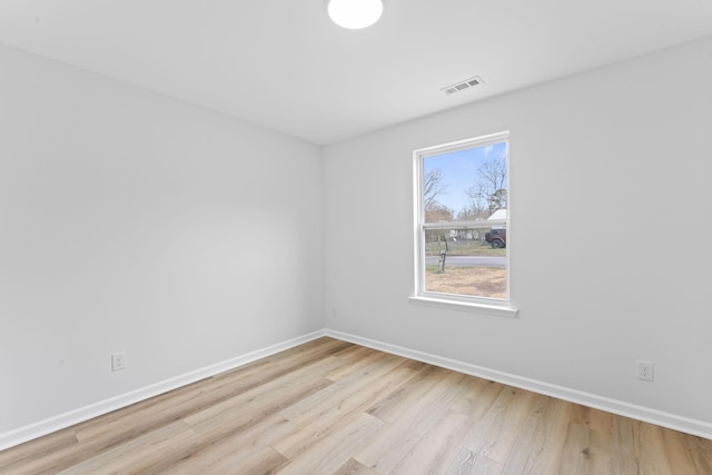 empty room featuring light wood-style flooring, visible vents, and baseboards