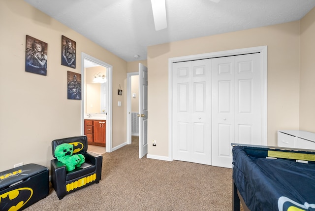 carpeted bedroom featuring a closet, ensuite bath, and ceiling fan