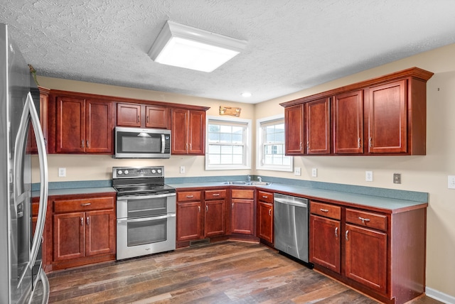 kitchen featuring a textured ceiling, stainless steel appliances, dark wood-type flooring, and sink