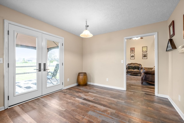 unfurnished dining area with a textured ceiling, dark wood-type flooring, and french doors