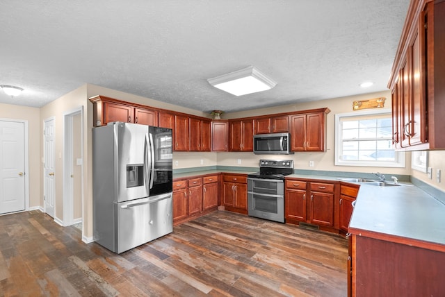 kitchen with dark hardwood / wood-style flooring, stainless steel appliances, a textured ceiling, and sink