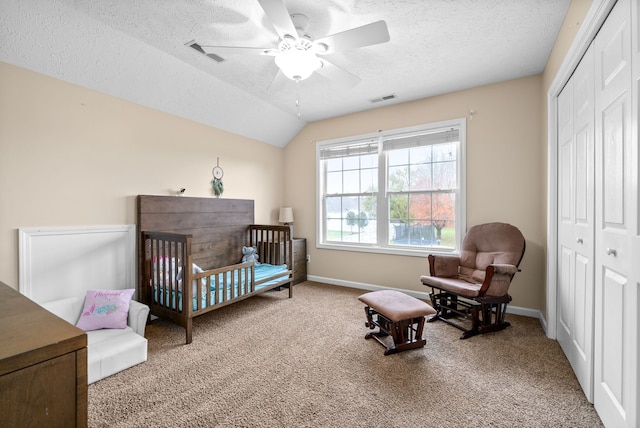 carpeted bedroom featuring a crib, ceiling fan, a closet, and vaulted ceiling