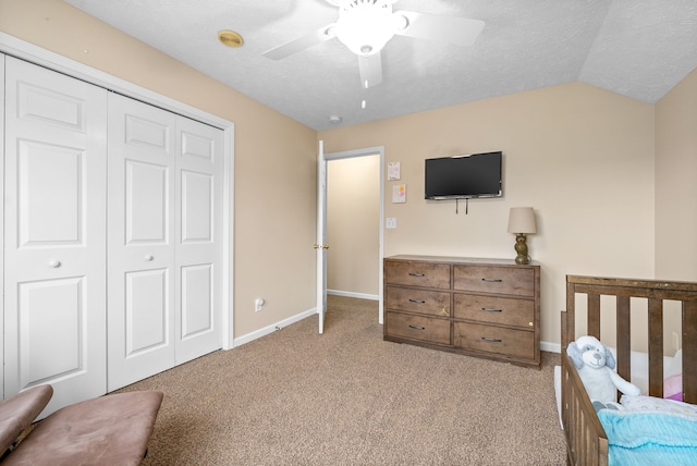 carpeted bedroom with ceiling fan, lofted ceiling, a textured ceiling, and a closet