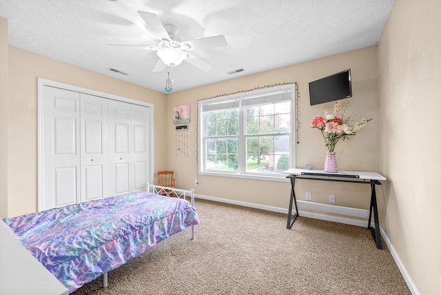 bedroom featuring ceiling fan, a closet, carpet floors, and a textured ceiling