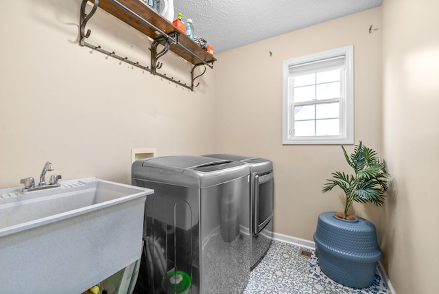 laundry room featuring a textured ceiling, independent washer and dryer, and sink