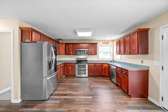 kitchen with a textured ceiling, stainless steel appliances, dark hardwood / wood-style floors, and sink