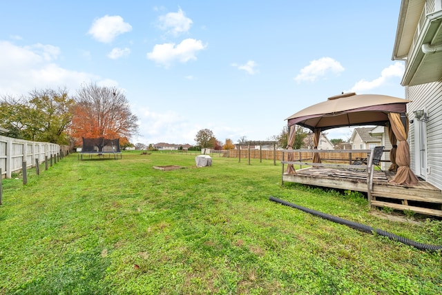 view of yard featuring a gazebo, a trampoline, and a wooden deck