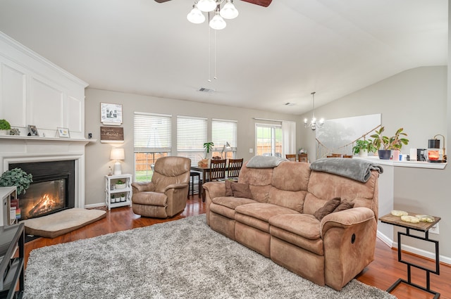 living room with ceiling fan with notable chandelier, dark wood-type flooring, and lofted ceiling