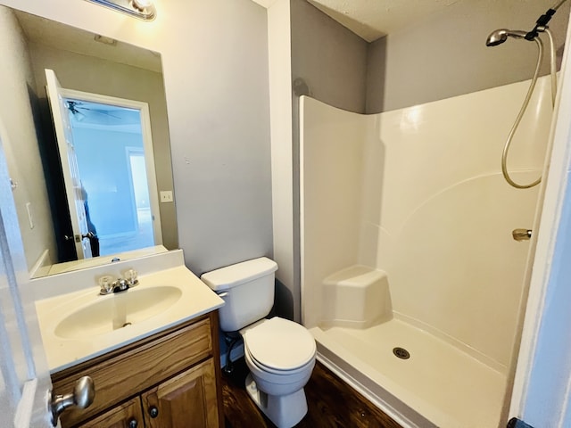 bathroom with a shower, vanity, toilet, and ceiling fan