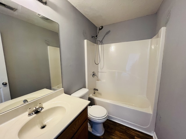 full bathroom with vanity, a textured ceiling,  shower combination, wood-type flooring, and toilet