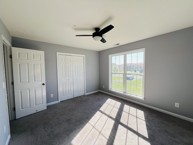 unfurnished bedroom featuring ceiling fan, a closet, and dark carpet