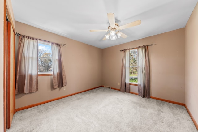 carpeted empty room featuring ceiling fan and plenty of natural light