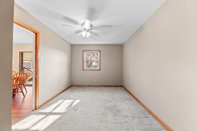 carpeted spare room with ceiling fan and a textured ceiling