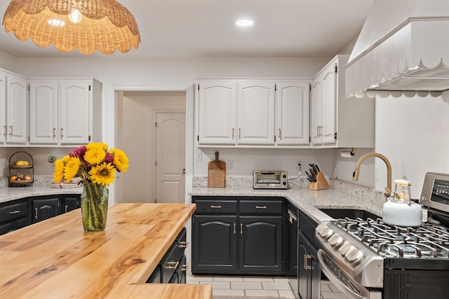 kitchen featuring white cabinets, sink, gas range, light tile patterned floors, and butcher block counters