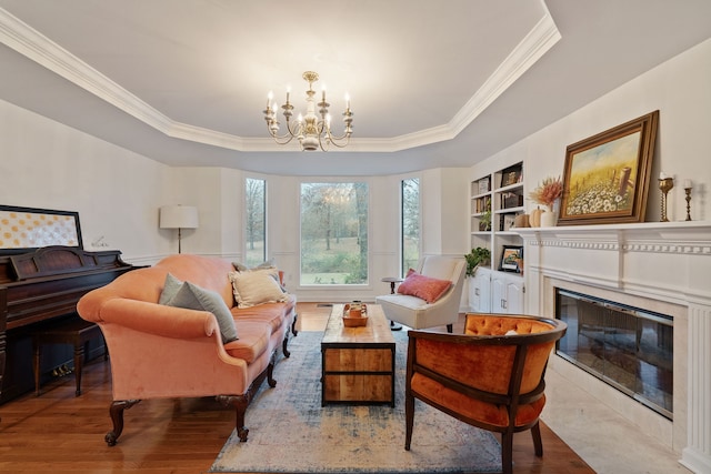 living area with a fireplace, light wood-type flooring, a tray ceiling, and an inviting chandelier