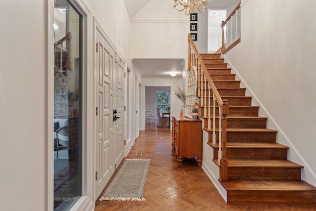 foyer entrance featuring a high ceiling, a notable chandelier, and parquet flooring