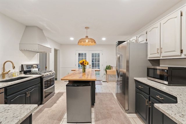 kitchen featuring white cabinetry, sink, french doors, premium range hood, and appliances with stainless steel finishes