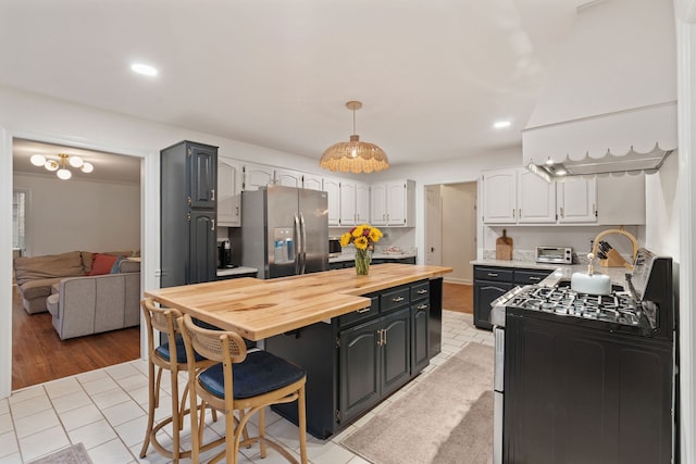 kitchen with hanging light fixtures, light hardwood / wood-style flooring, white cabinetry, butcher block counters, and stainless steel appliances