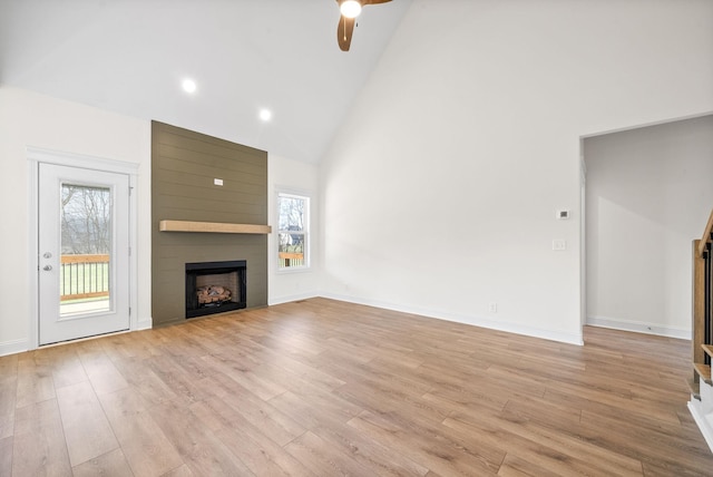 unfurnished living room featuring ceiling fan, a large fireplace, high vaulted ceiling, and light hardwood / wood-style flooring