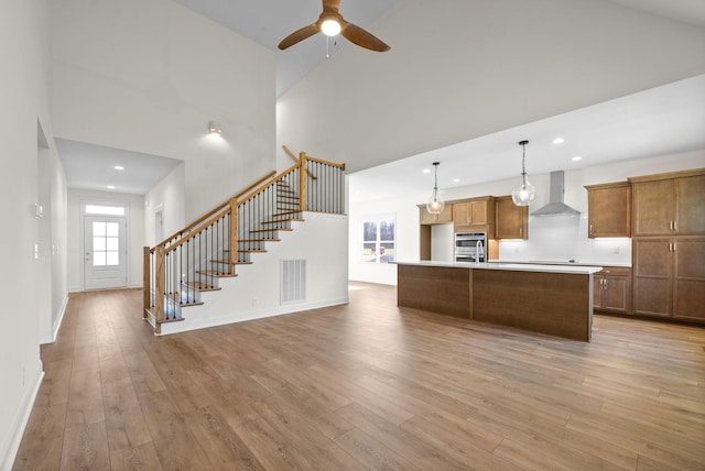 kitchen with a center island, decorative light fixtures, wall chimney range hood, and light hardwood / wood-style floors