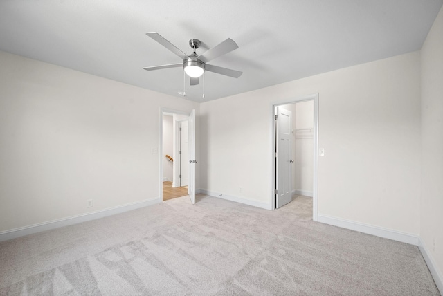 unfurnished bedroom featuring a closet, a spacious closet, ceiling fan, and light colored carpet