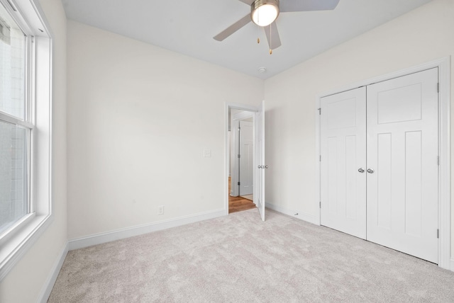 unfurnished bedroom featuring a closet, light colored carpet, and ceiling fan