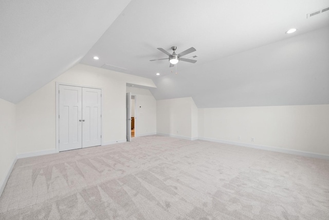 additional living space with ceiling fan, light colored carpet, and vaulted ceiling