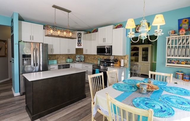 kitchen featuring backsplash, white cabinetry, hanging light fixtures, and appliances with stainless steel finishes