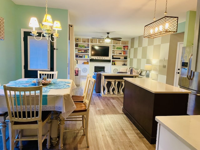 dining room with light hardwood / wood-style flooring and ceiling fan with notable chandelier