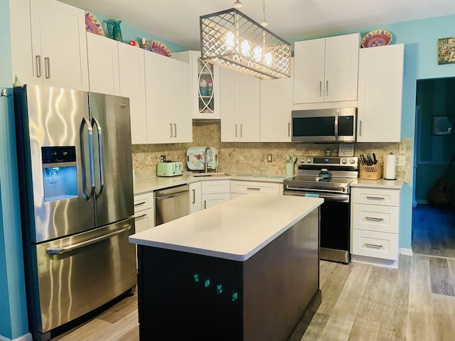 kitchen with appliances with stainless steel finishes, white cabinetry, a kitchen island, and light hardwood / wood-style flooring