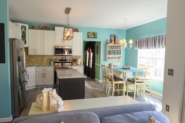 kitchen featuring pendant lighting, dark hardwood / wood-style floors, a kitchen island, white cabinetry, and stainless steel appliances