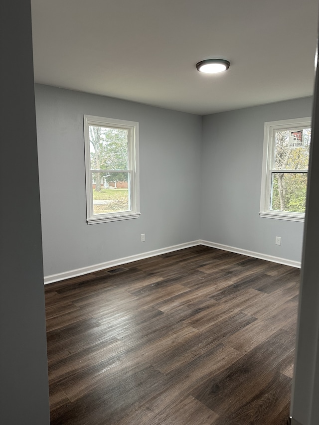 empty room featuring dark wood-type flooring and a healthy amount of sunlight